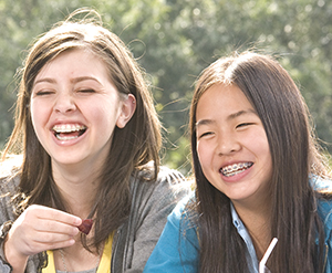 Two girls wearing braces and laughing.
